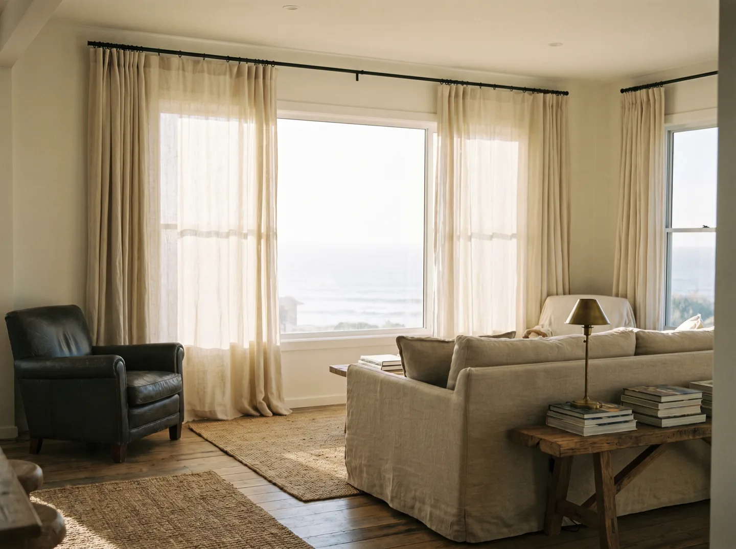 Heavy natural linen drapes hung floor length in a bright coastal living room